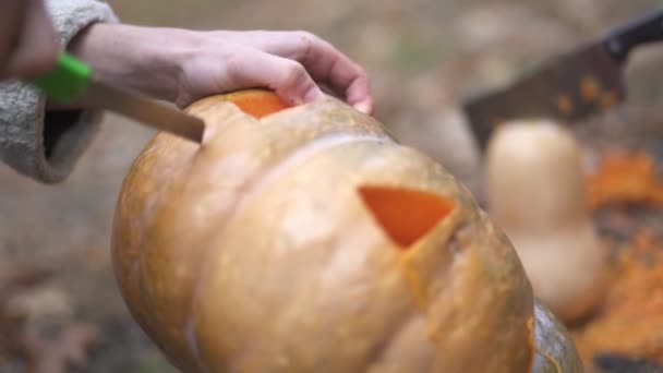 Halloween. Mannelijke handen snijden een halloween pompoen. — Stockvideo