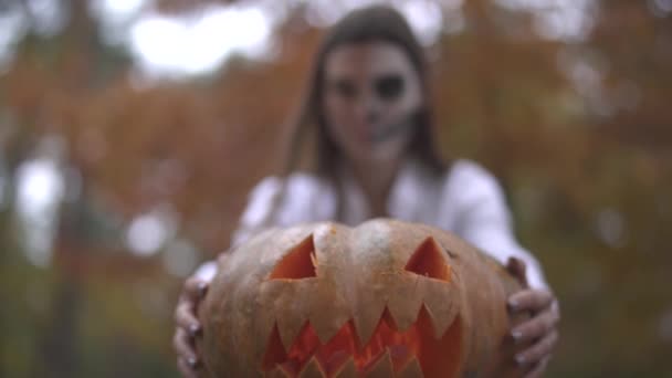 Halloween. Chica con un aterrador maquillaje de Halloween sosteniendo una calabaza en sus manos — Vídeos de Stock