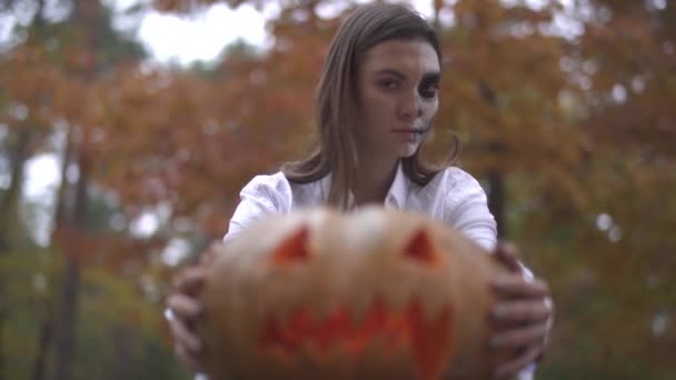 Хеллоуїн. Жінка з страшним макіяжем на Хеллоуїн тримає гарбуз в руках — стокове відео