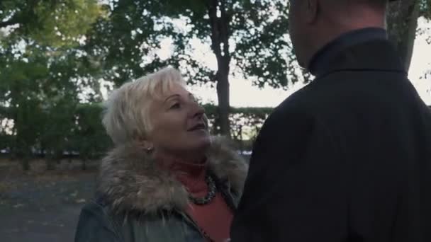 Donna matura sta raccontando la storia a uomo alto al parco — Video Stock