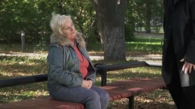 Kadın parkta yakınındaki olgun adam oturur