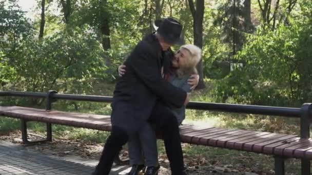 Pareja adulta abrazándose en un banco del parque . — Vídeo de stock
