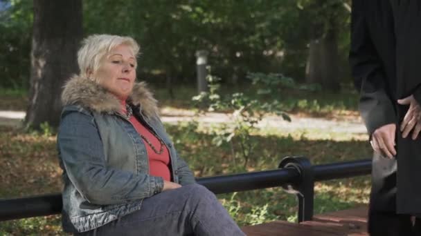 Adult man sits next to an adult woman on a park bench. — Stock Video