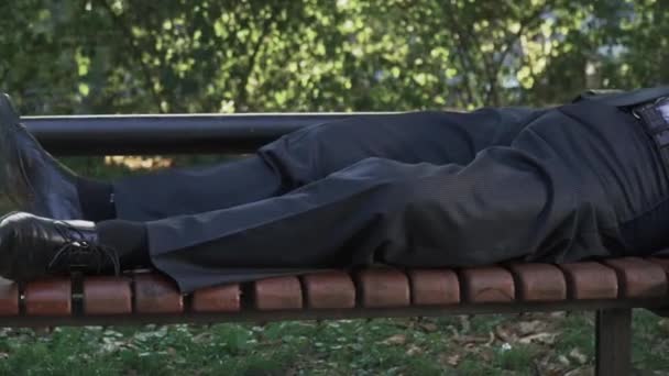 Um bêbado dorme no banco do parque. — Vídeo de Stock