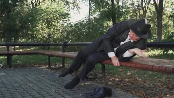 Bêbado homem coloca confortável no banco no parque — Vídeo de Stock
