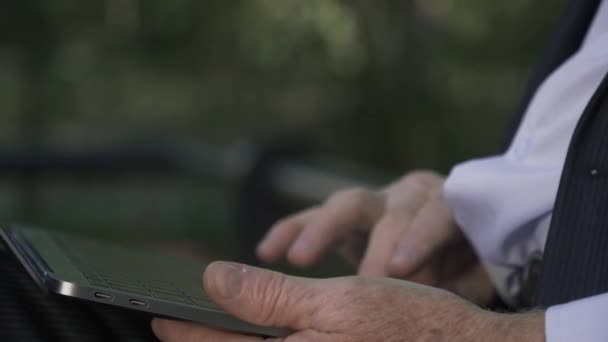 Mãos masculinas sênior está trabalhando em netbook no parque — Vídeo de Stock