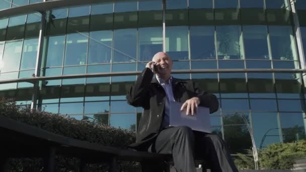 Volwassen man praten over de telefoon in de buurt van het business center — Stockvideo