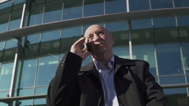 Hombre adulto hablando por teléfono en el fondo del centro de negocios — Vídeos de Stock