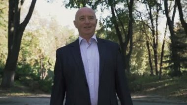 Yaşlı adam parkta yürüyüş ve gülümseyen