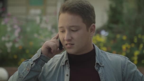 Lachende jonge man praten over de telefoon — Stockvideo