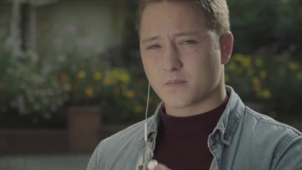 Um homem bonito de camisa jeans olha para a câmara. Cara de perto — Vídeo de Stock