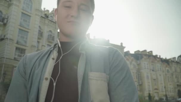 Молодой человек в наушниках слушает музыку — стоковое видео