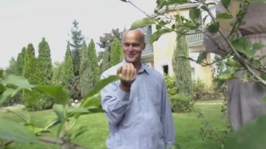 Bir elma elinde tutan ve gülümseyen yakışıklı kel adam