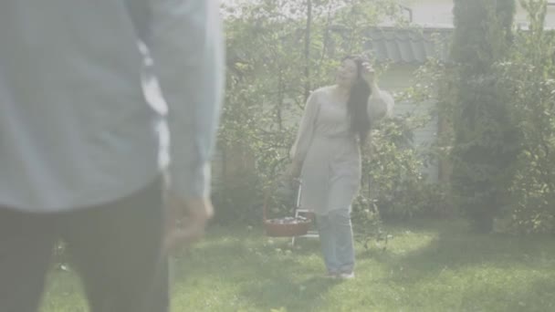 Mature woman with a basket goes to her husband in the garden — Stock Video