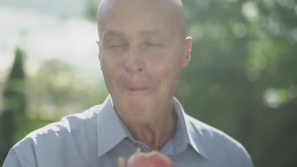 O careca está a comer uma maçã. Close-up — Vídeo de Stock