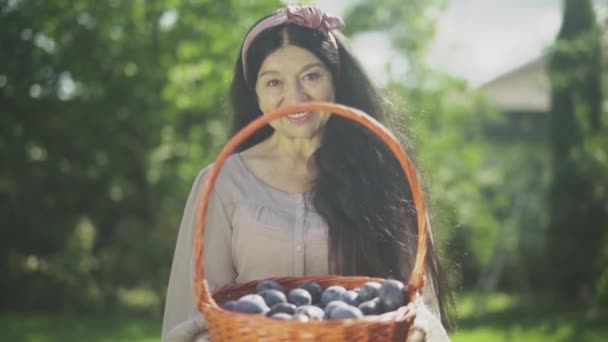 Velha mulher sorridente segurando uma cesta com ameixas — Vídeo de Stock