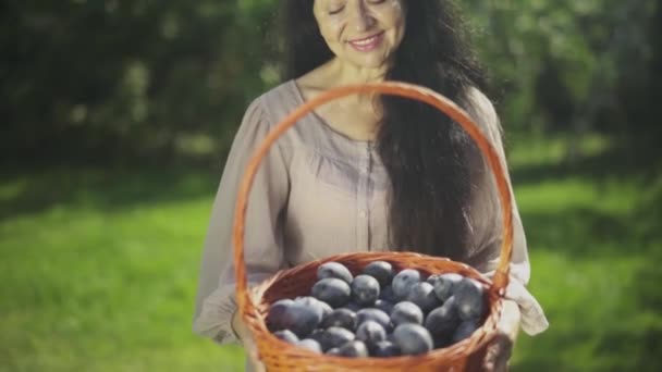 Mooie rijpe vrouw met een mand met pruimen — Stockvideo