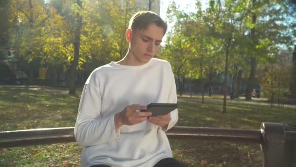Junger Mann liest im Park ein Buch — Stockvideo