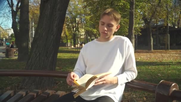 Estudiante está leyendo un libro en el parque — Vídeo de stock