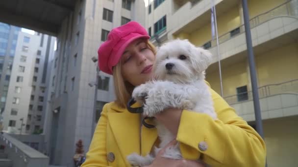 Blond dam gnuggar ansiktet på hunden på city — Stockvideo