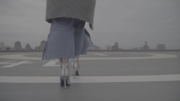 Femme en chaussures argentées va dans le contexte des bâtiments urbains. S-log — Video