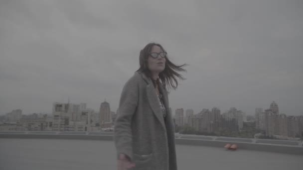 Nettes Mädchen geht auf den Hintergrund der Stadtansicht. Zeitlupe, s-log, ungraded — Stockvideo