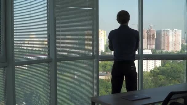 Молодий чоловік стоїть перед вікном і по телефону . — стокове відео
