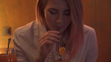 Güzel bir genç kız bir kulüpte kokteyl içme portresi