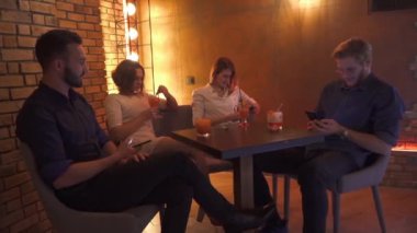 Masada oturan ve telefonları içine bakarak iki genç çiftler