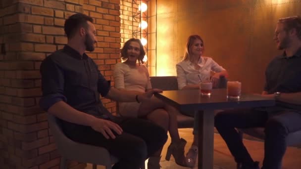 Vidám társaság a fiatalok pihen egy asztalnál egy kávézóban — Stock videók