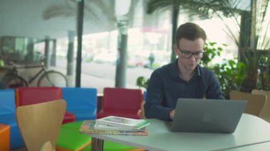 Genç adam ile laptop kütüphanede çalışıyor