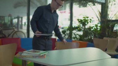 Netbook ile genç adam gelir ve modern Kütüphane masada oturur