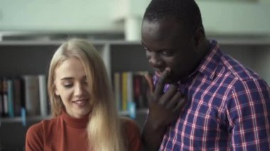 Güzel kadın ve Afrika kökenli Amerikalı adam kitap kütüphanede tartışmak