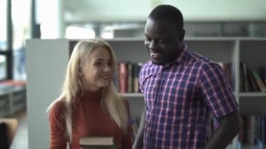 Güzel bayan ve Afrikalı-Amerikalı kütüphanede kitap tartışmak