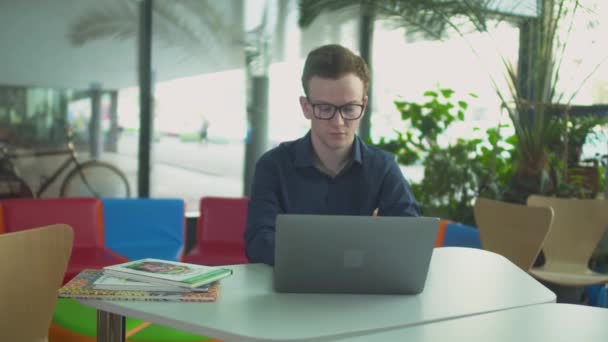 El estudiante está trabajando con el ordenador portátil en la biblioteca — Vídeo de stock