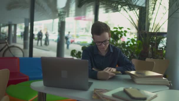 Young man is searching information in the book in the library — Stock Video