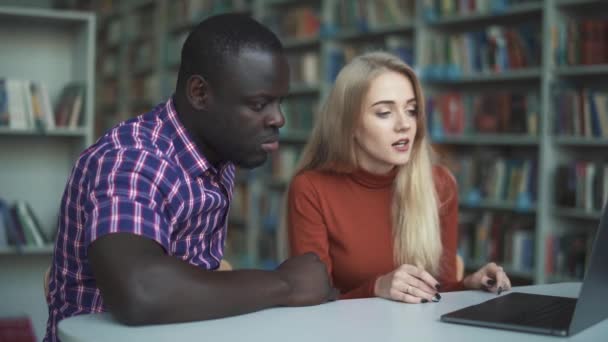 Menina caucasiana se comunica com a americana africana e mostra em laptops — Vídeo de Stock