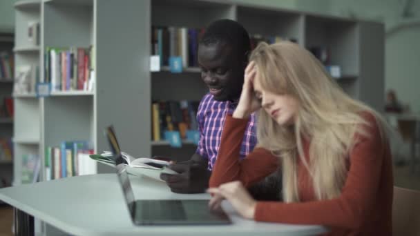 Estudiantes internacionales estudian juntos en la biblioteca — Vídeo de stock