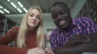 Afro-Amerikan erkek ve Avrupa kadın kamera kütüphanede konuşmak