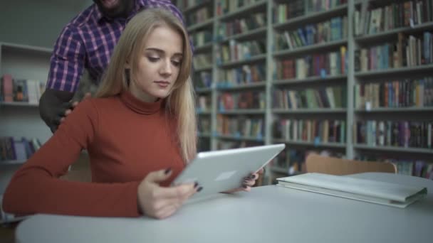 Hombre afroamericano y mujer europea se han reunido en la biblioteca — Vídeos de Stock