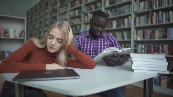 Afroamerikanska manliga och europeisk kvinna somnar i biblioteket — Stockvideo