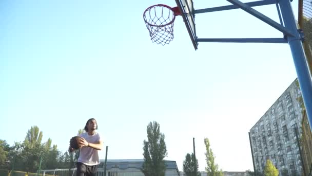 Killen kastar en basketboll i basket netto. — Stockvideo