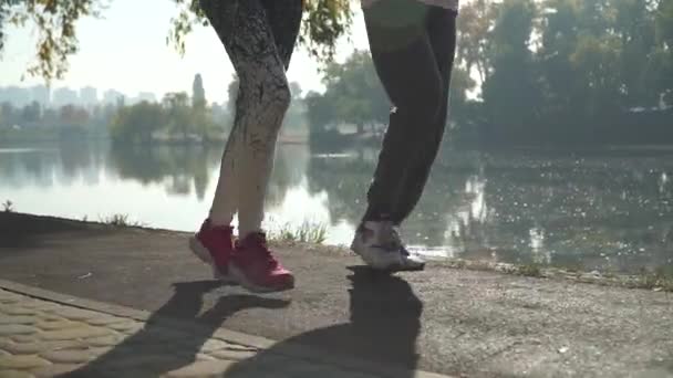 Beine von männlichen und weiblichen Läufern in der Nähe des Flusses — Stockvideo
