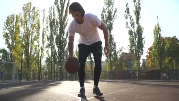 Joven hombre está jugando baloncesto al aire libre — Vídeos de Stock