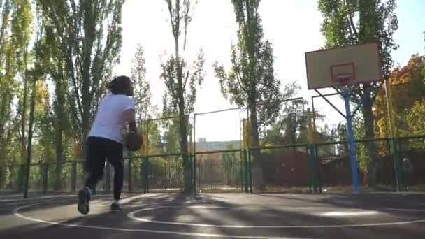Молодой парень на детской площадке бросает мяч — стоковое видео