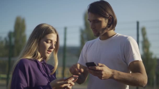 Pareja joven intercambian sus teléfonos — Vídeo de stock