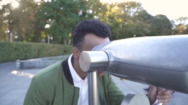 Afro-americano olha em visualizador binocular em paisagem urbana . — Vídeo de Stock