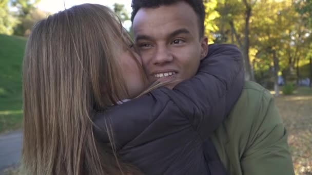 African American en Kaukasische meisje knuffelen en zoenen buitenshuis — Stockvideo