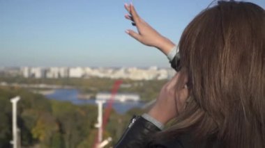 Kız şehir görünümün arka planına karşı telefonda konuşuyor.