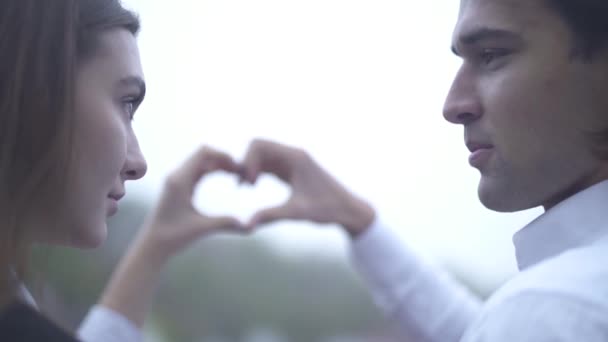 Hermosa pareja hacer un corazón con sus manos al aire libre Joven pareja pasa tiempo juntos Pareja en el amor — Vídeos de Stock